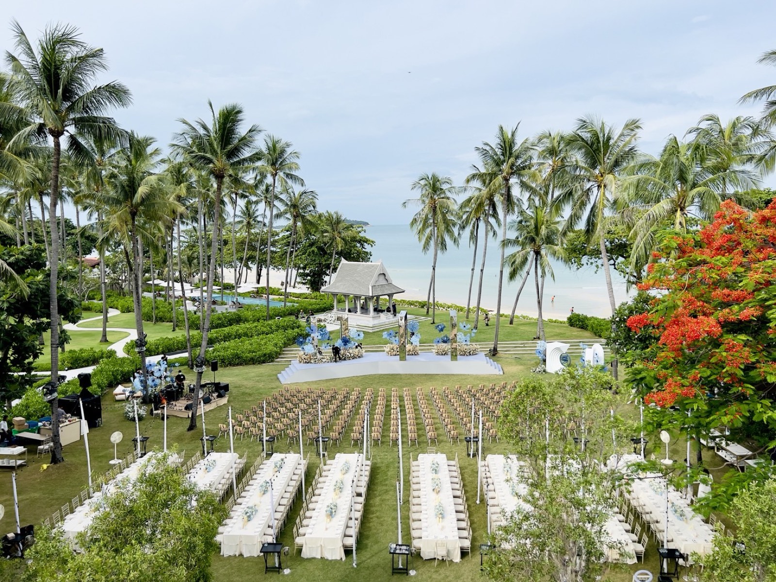 An elevated view of a large garden wedding reception at Centara Reserve Samui, banquet tables under the palms around the sala pavilion