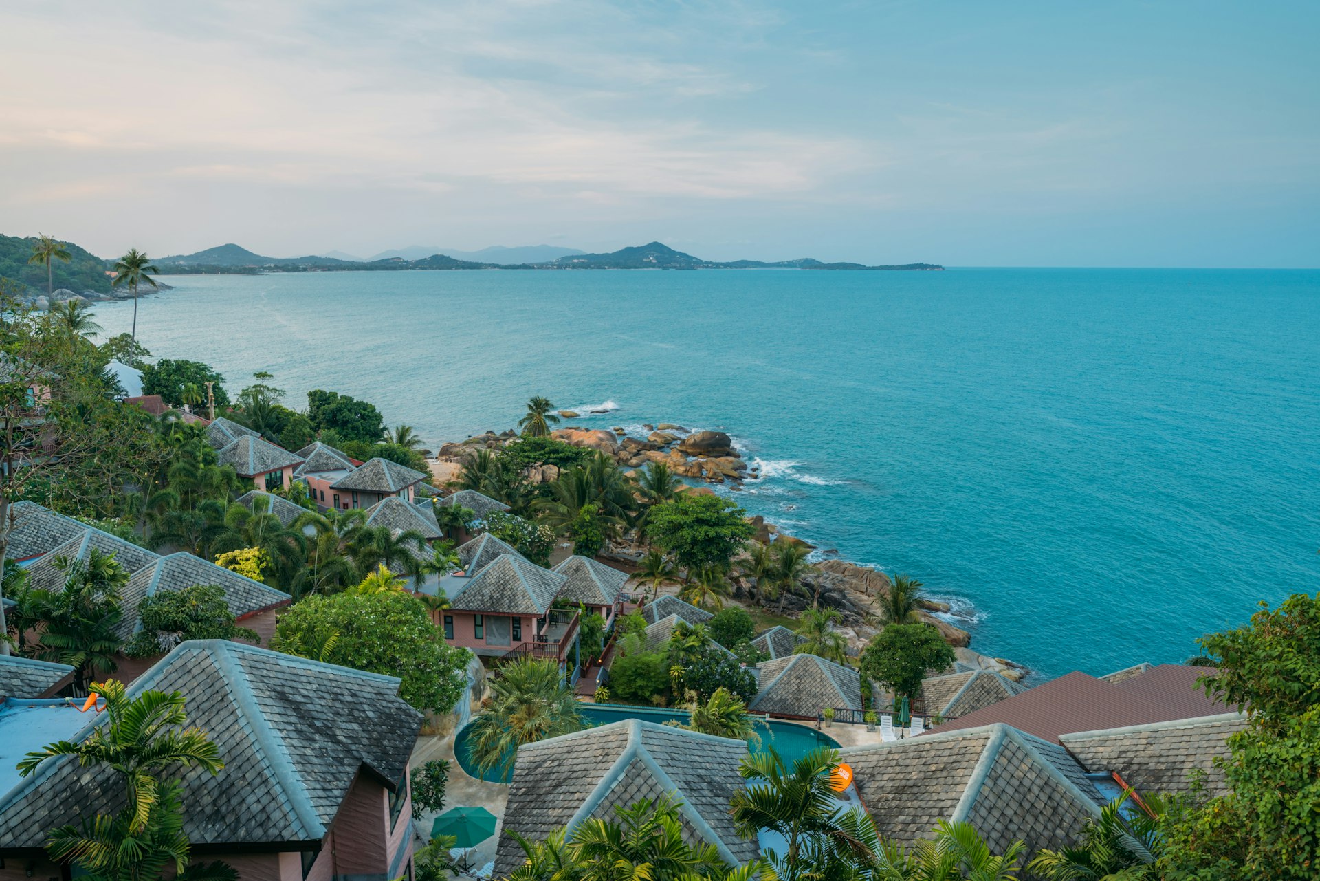 Aerial view of the Koh Samui coastline on approach, with villas set among palms above turquoise water