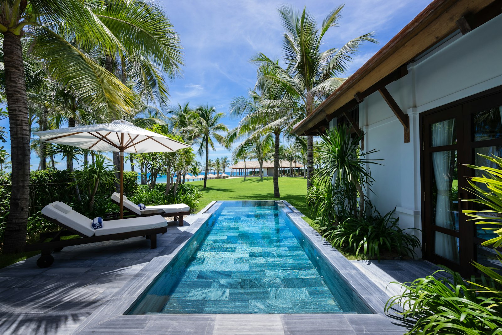 Private pool villa on Koh Samui with loungers and a lawn running toward the sea